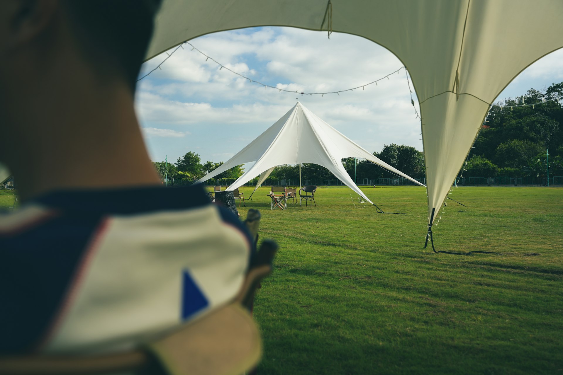 a man standing in a field next to a white tent