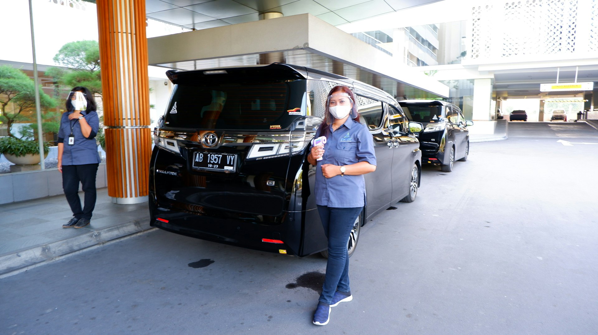 man in blue dress shirt and blue denim jeans standing beside black car